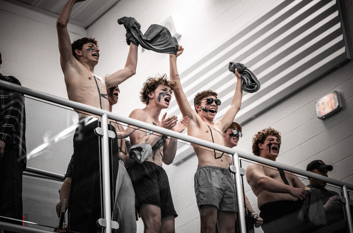 Jude Eckerle (Class of 2024), Robbie Koester (11), Griffin Barlow (12), Matthew Meyers (11), Noah Gracey (11), and Brody Cook (12) cheer for the girls swim team at Semi-State.
